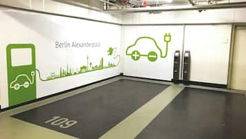A clean, modern electric vehicle charging station area with a cityscape mural on the wall and a clear floor marking.
