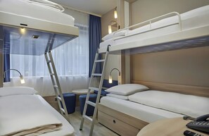 A hotel room with bunk beds, a desk, a chair, a ladder, a bedside table with a lamp, and a phone. - Leonardo Smart Hotel Berlin Alexanderplatz (Berlin)
