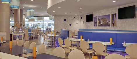Un restaurante moderno con mesas redondas, asientos tipo banqueta en azul y un techo curvo.