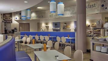 A modern cafe with seating areas, tables, and a counter with food and drink options.