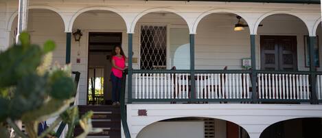 A two-story building with a covered porch and a staircase leading to the entrance.