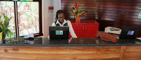 A reception desk with a computer, a plant, and a red cabinet.