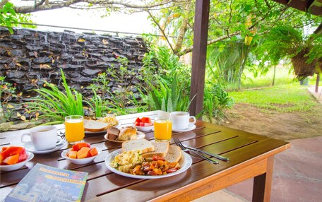 A breakfast table with plates of food, a cup of coffee, and a glass of orange juice.