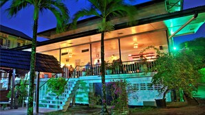 A modern hotel with a glass facade, outdoor seating, and a staircase leading to the upper level. - Eco Torarica (Paramaribo)