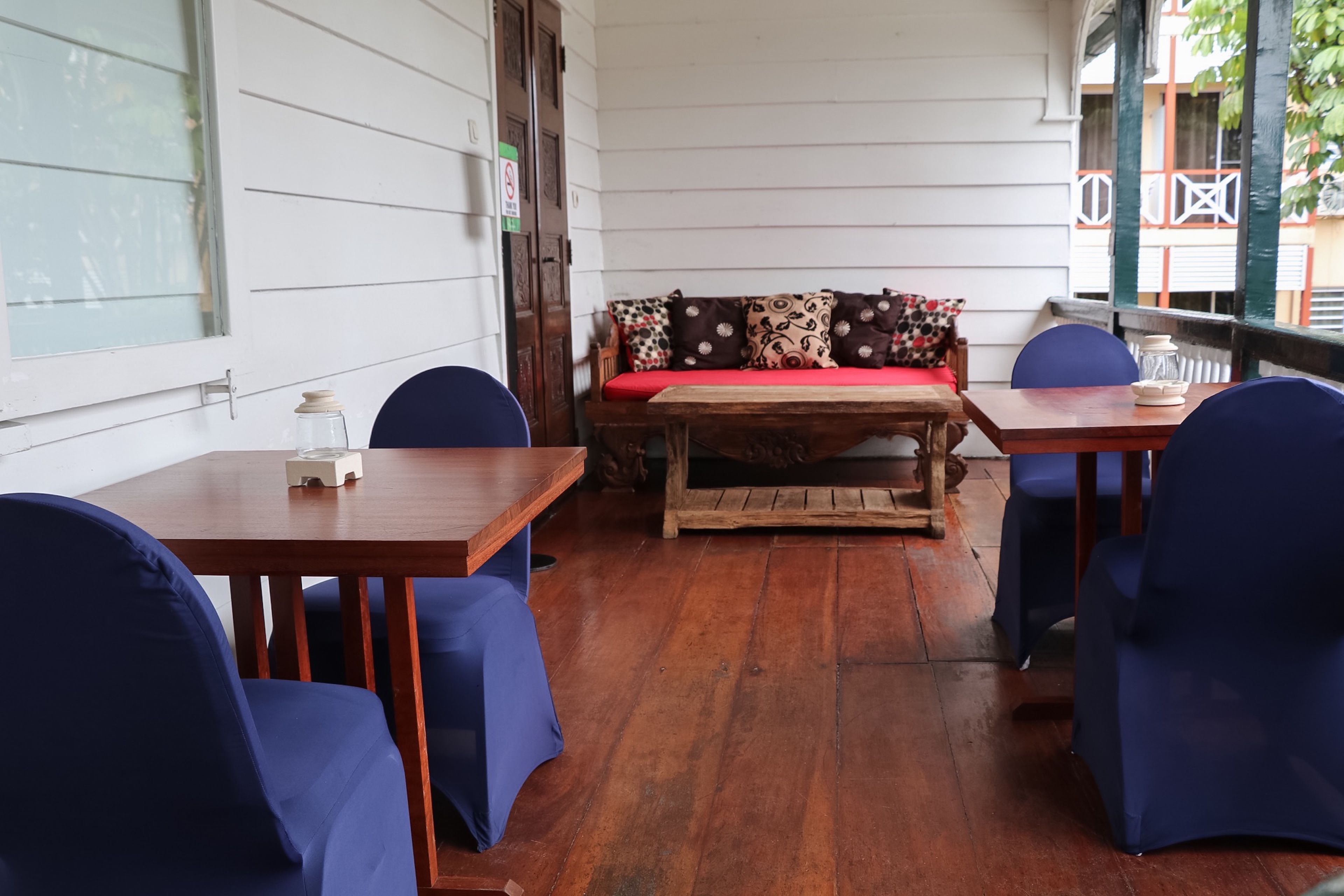 A wooden table with chairs, a bench with patterned cushions, and a window with blinds.