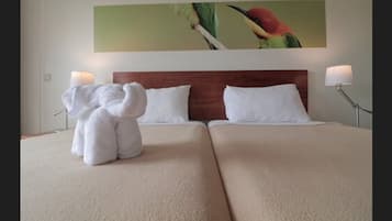 A hotel room with two beds, a wooden headboard, and a painting of a bird on the wall.