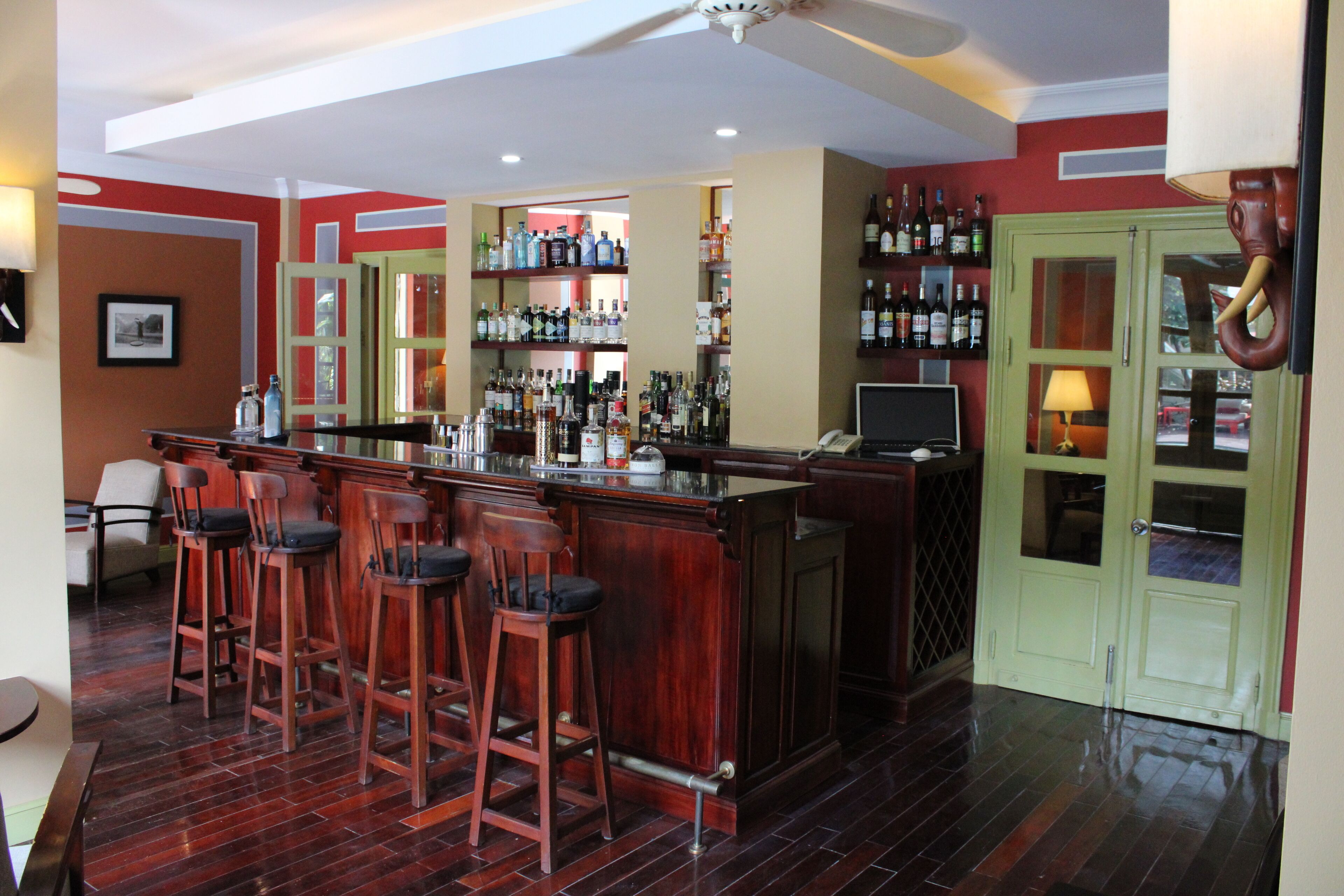 Zona de bar con taburetes de madera, barra y estanterías llenas de botellas.