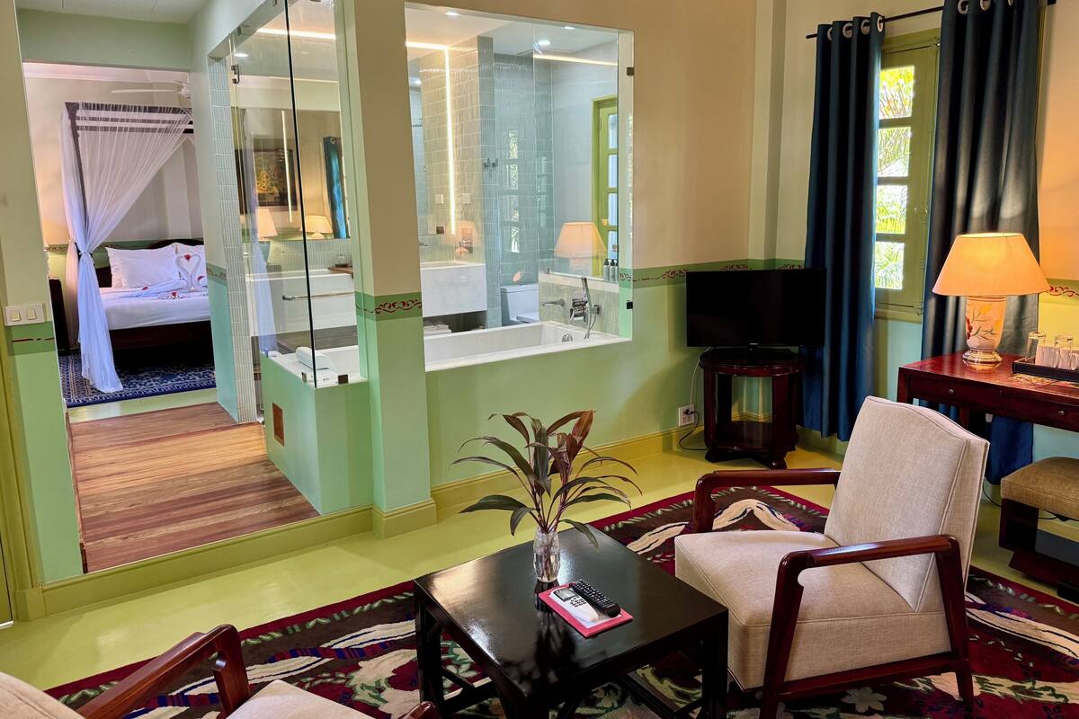Una habitación de hotel con cama, baño, televisión, una mesa con control remoto y una silla.