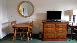 Une pièce comprenant un bureau en bois, une télévision, un miroir et une chaise.