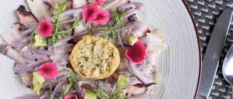 Ein Teller mit Essen, darunter ein Oktopus, Blumen und ein runder Cracker.
