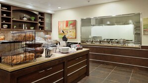 A buffet setup with bread, condiments, and various dishes.