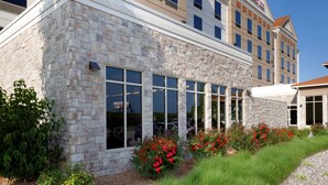 A hotel with a stone facade, large windows, and a clear blue sky.