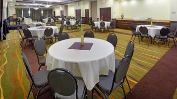 A conference room with multiple round tables, each surrounded by chairs, and a carpeted floor with a wavy pattern.