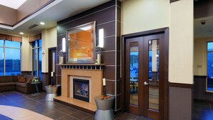 A lobby with a fireplace, large windows, and a view of the outdoors.