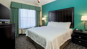 Une chambre d’hôtel avec un grand lit, un téléviseur à écran plat, un ventilateur de plafond et une fenêtre avec des rideaux.