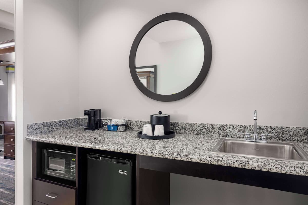 A compact kitchen with a built-in microwave, dishwasher, and sink. A coffee maker and a tea kettle are on the counter.
