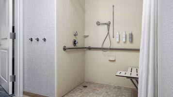 A shower area with a grab bar, a handheld showerhead, and a handheld shower attachment.