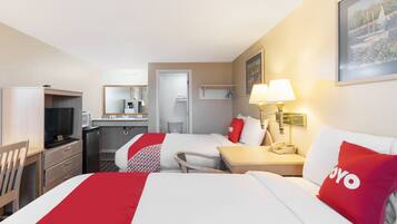 Quarto de hotel com duas camas, uma mesa, uma televisão e banheiro.