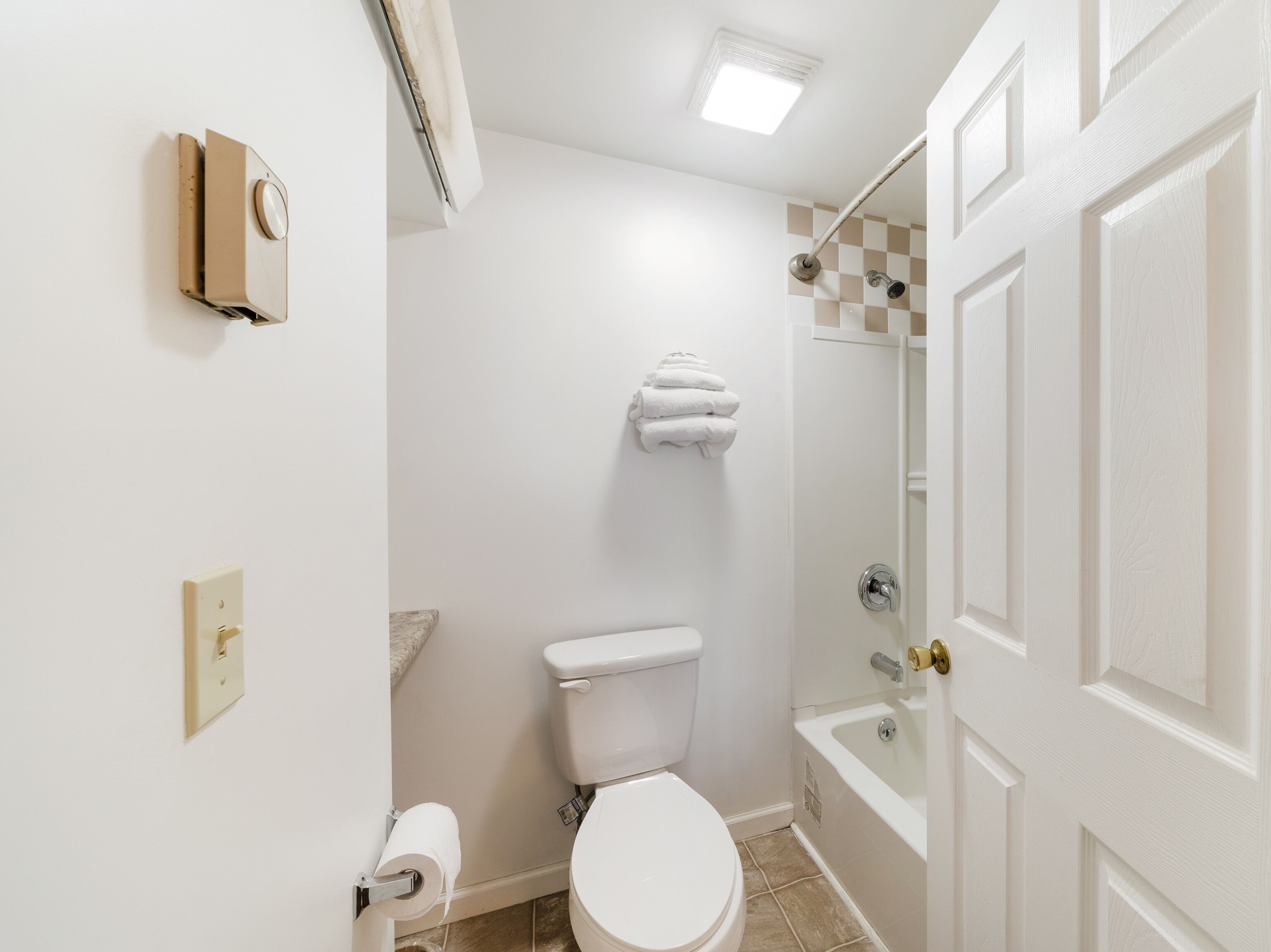 Un baño con inodoro, ducha, toallero y puerta.