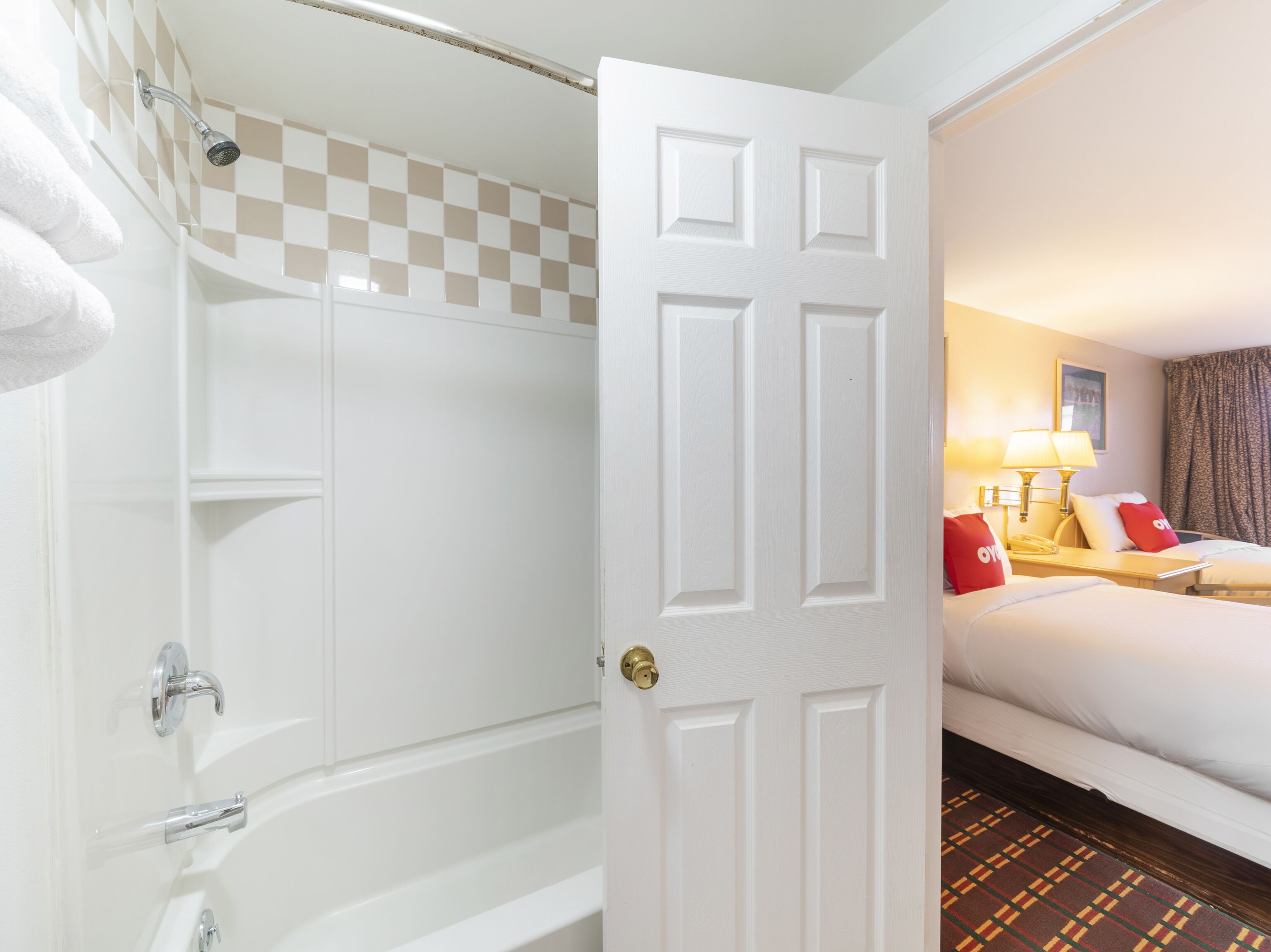 Une chambre d’hôtel avec une douche, un lit, une table de chevet avec des lampes et un sol à carreaux.