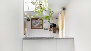 A kitchen with a hanging plant, a clock, and a framed picture on the wall. - OYO Hotel Starlite Seneca Falls (Seneca Falls)