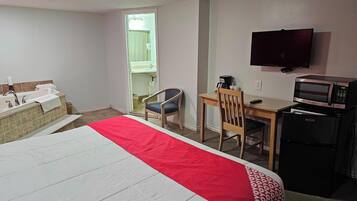 Hotelkamer met een bed, een bureau, een stoel, een televisie, een magnetron en een wastafel.
