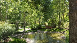 A serene garden with a pond, a bench, and a variety of trees. - GetAways at Olympic Village Inn (Olympic Valley)