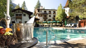 A poolside area with a table holding a bottle, a pitcher, and fruits. - GetAways at Olympic Village Inn (Olympic Valley)