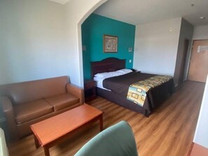 A room with a bed, a sofa, a small table, and a wall with a picture. - Tropicana Inn and Suites (Dallas)