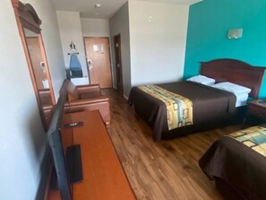 Quarto de hotel com cama, escrivaninha, cadeira e espelho.