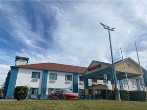 A hotel with a blue and white exterior, a red car parked in front, and a 'WELCOME!' sign on the roof. - Tropicana Inn and Suites (Dallas)