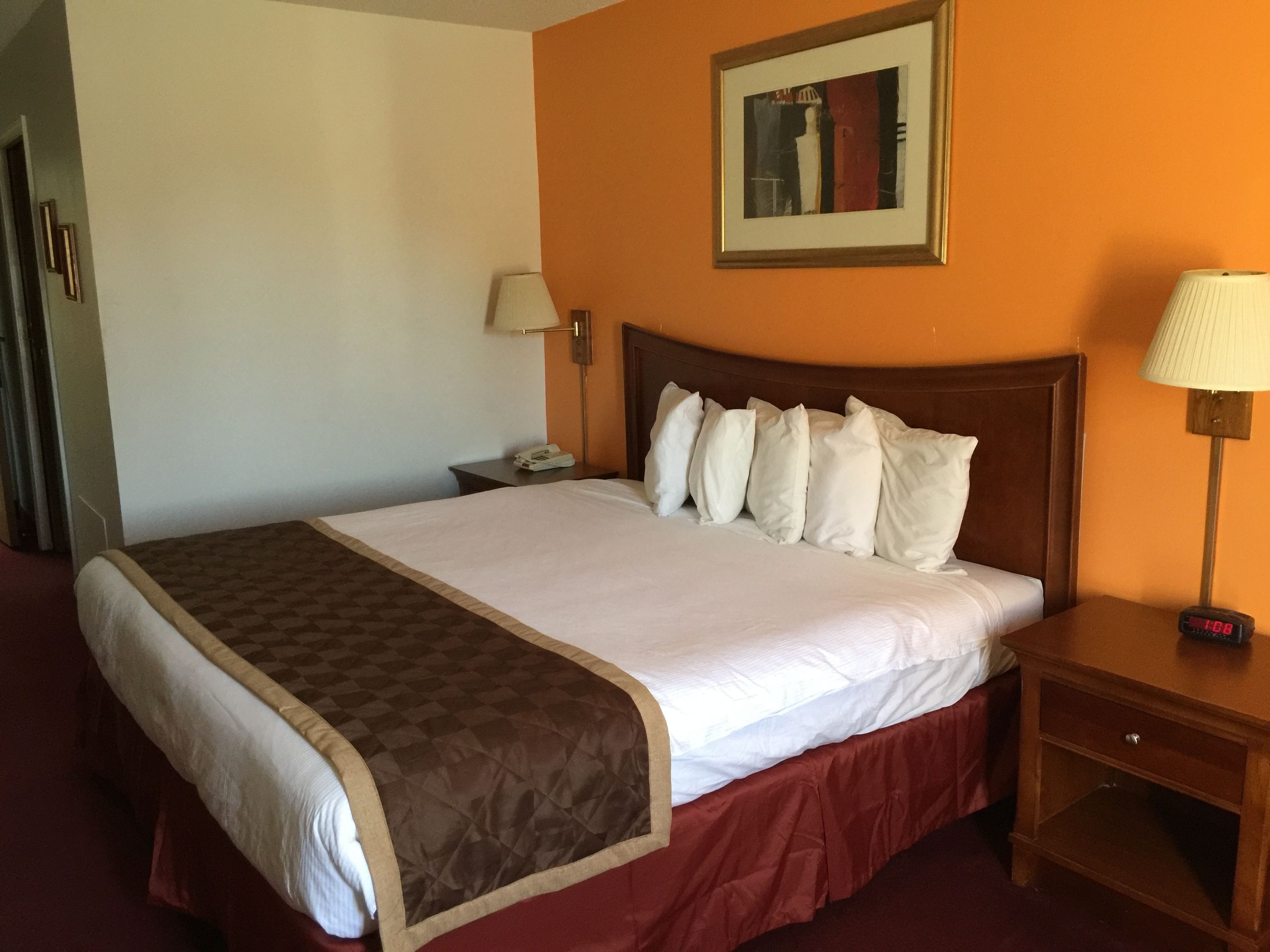 Habitación de hotel con una cama grande, una mesita de noche, una lámpara y un cuadro en la pared.