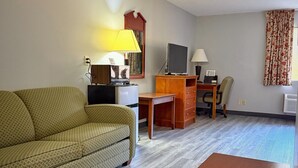 A furnished living room with a sofa, a wooden table, a TV, and a desk with a computer. - Laketree Inn And Suites Marion (Marion)