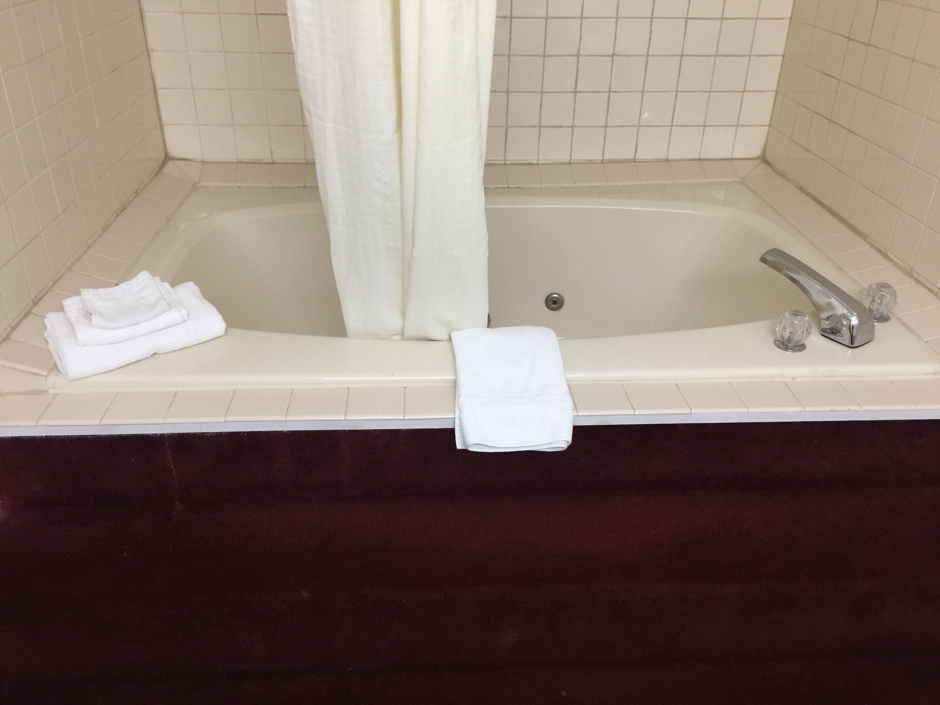 A bathtub with a white towel and a folded towel on the edge.