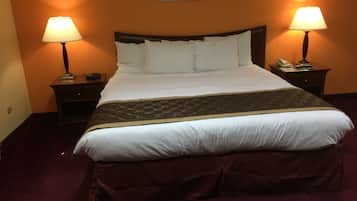 Een hotelkamer met een groot bed, twee nachtkastjes met lampen, een telefoon en een schilderij aan de muur.