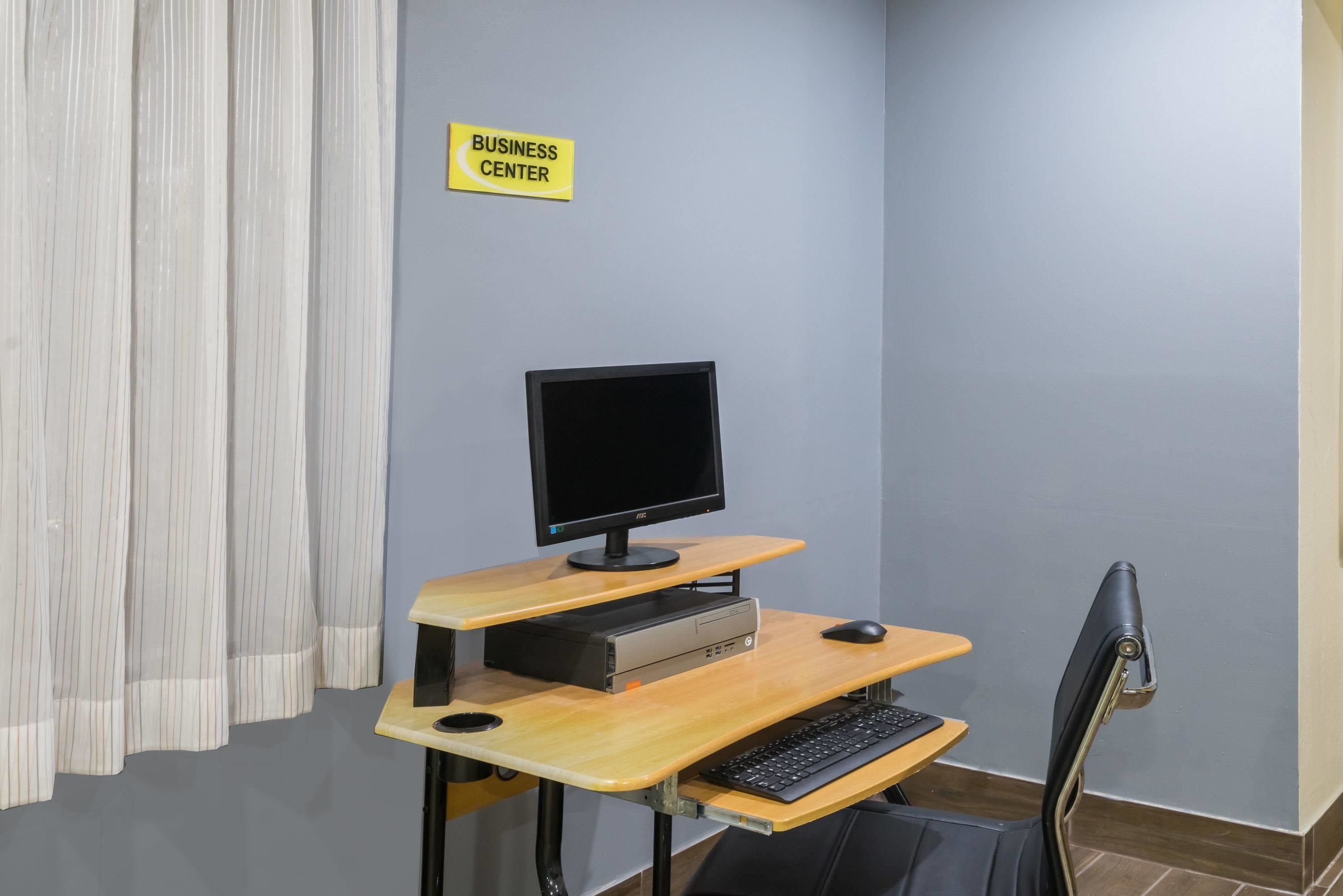 A business center with a computer desk, a monitor, keyboard, and mouse.