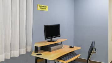 A business center with a computer desk, a monitor, keyboard, and mouse.