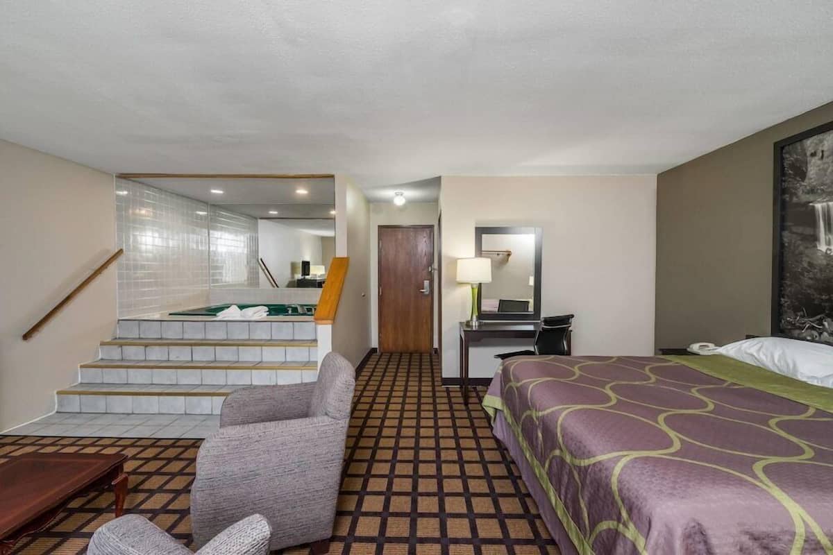 A hotel room with a bed, a desk, a chair, a staircase, and a bathroom.