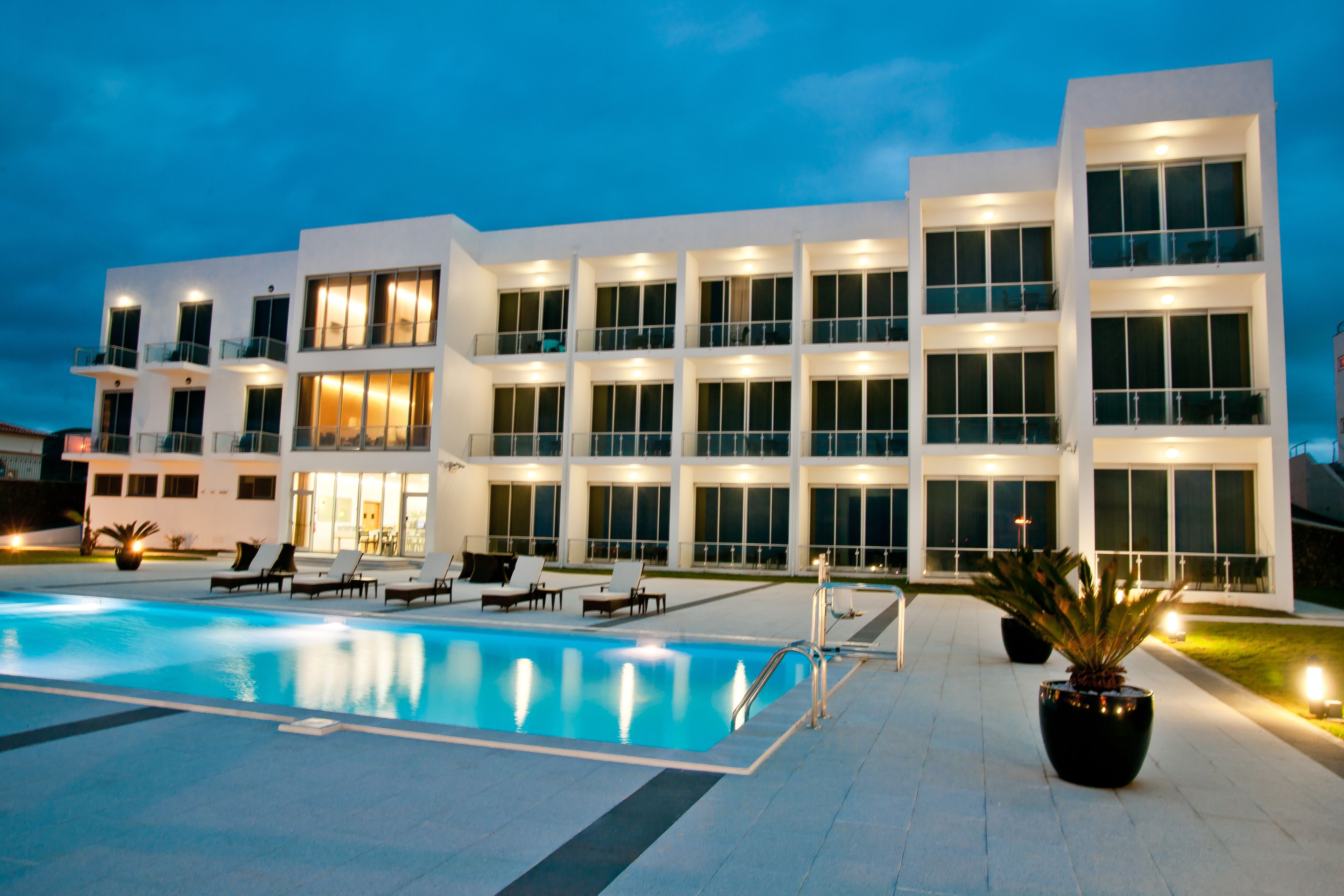 Un hôtel moderne doté d’une piscine, de nombreux balcons et de grandes fenêtres bien éclairées.