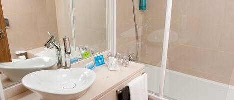 A bathroom with a sink, mirror, and shower.