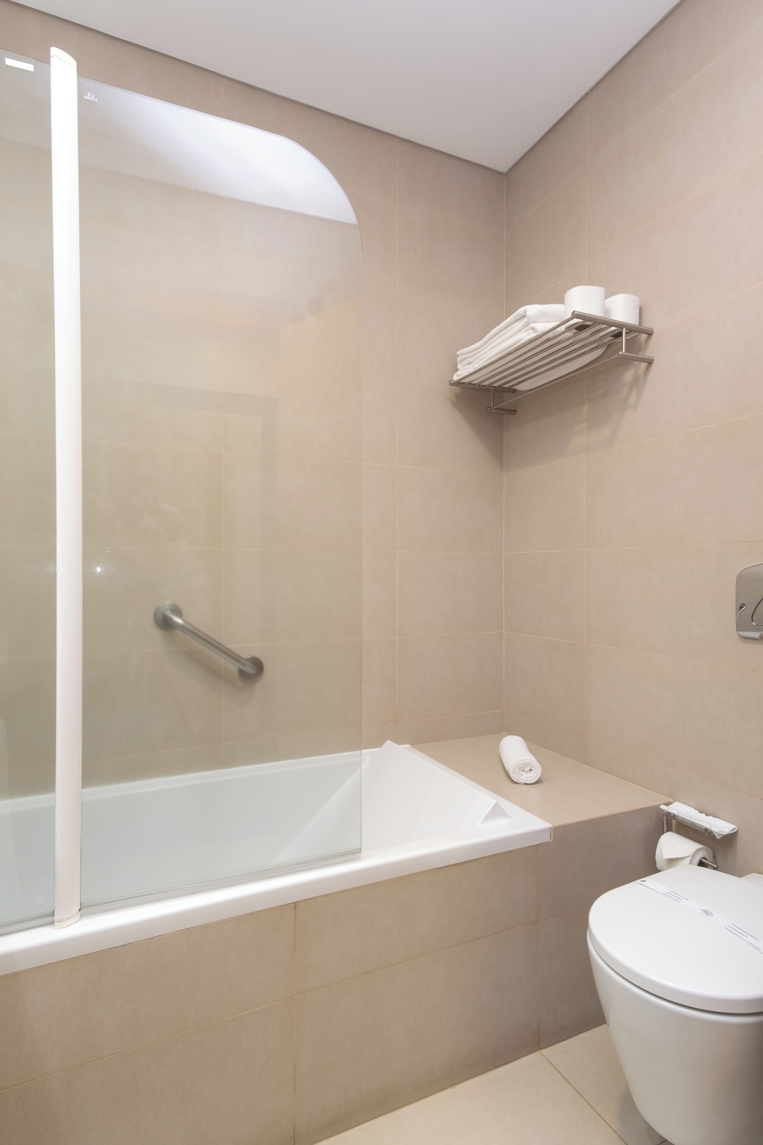 A modern bathroom with a glass-enclosed shower, a white bathtub, and a toilet.