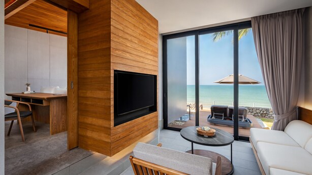 Una sala de estar moderna con televisor, comedor y vista al mar.