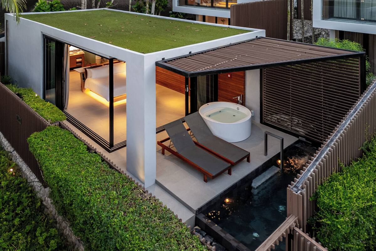A modern house with a glass-enclosed room, a hot tub, and a small pool.