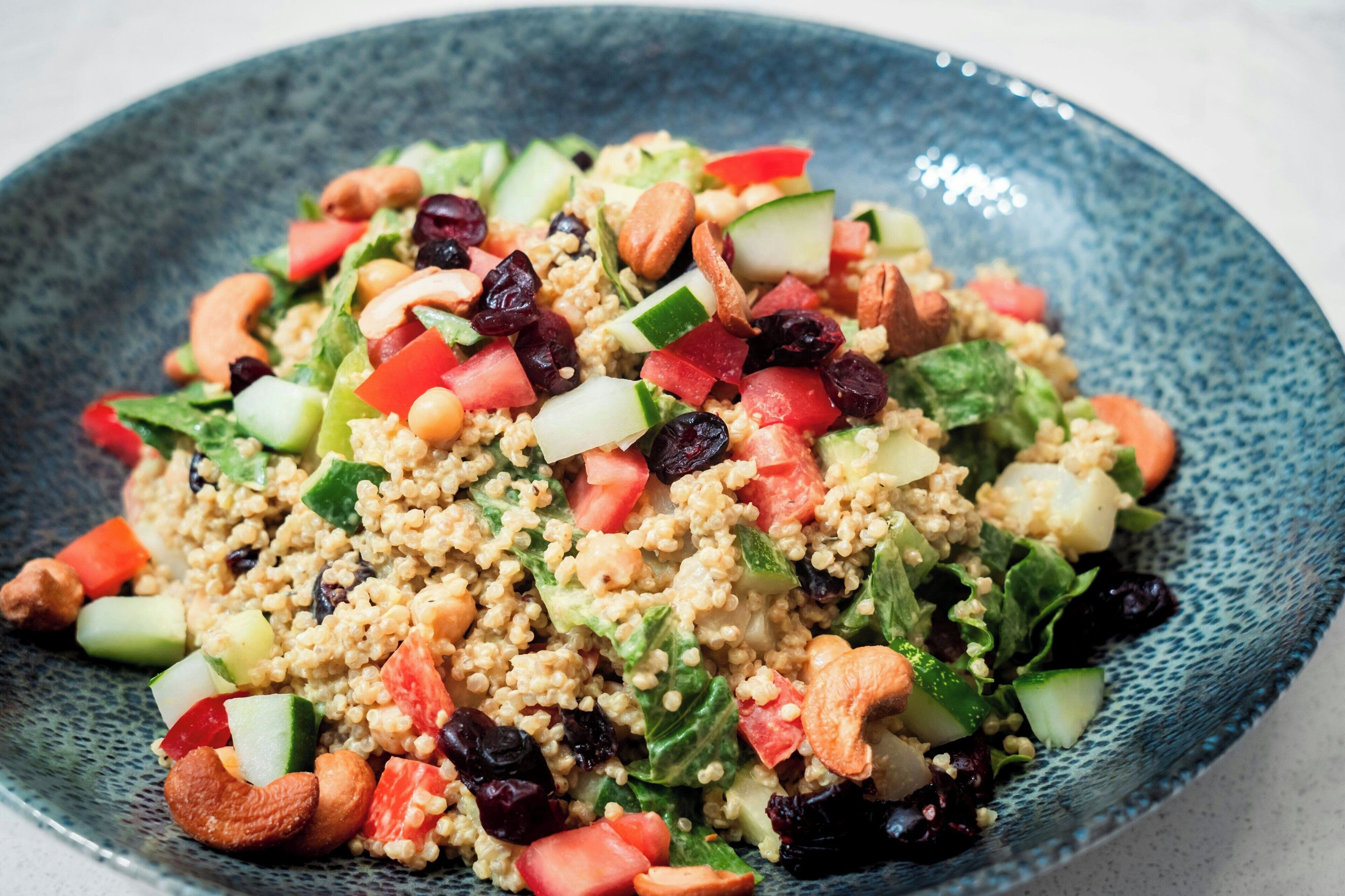 A bowl of quinoa salad with various vegetables and nuts.