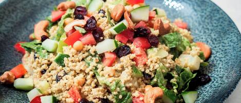A bowl of quinoa salad with various vegetables and nuts.