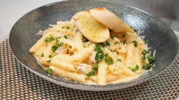 A plate of pasta with bread on a woven placemat.
