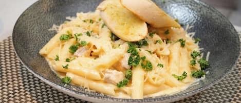 A plate of pasta with bread on a woven placemat.