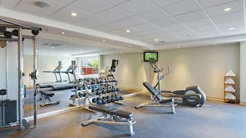 A gym with treadmills, weight machines, and dumbbells.