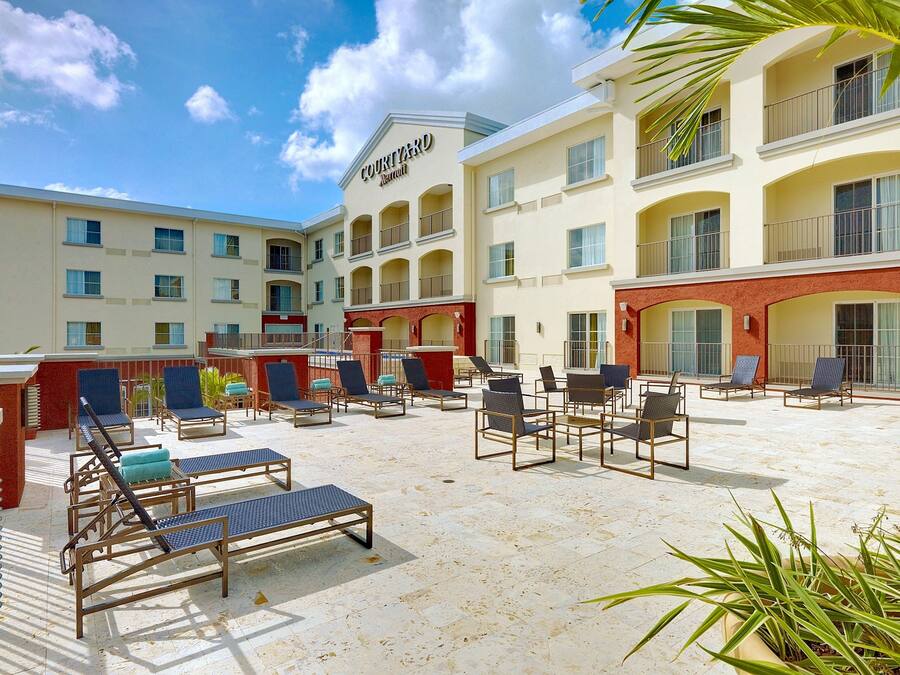 Un hotel Courtyard Marriott con asientos al aire libre y zona de piscina.