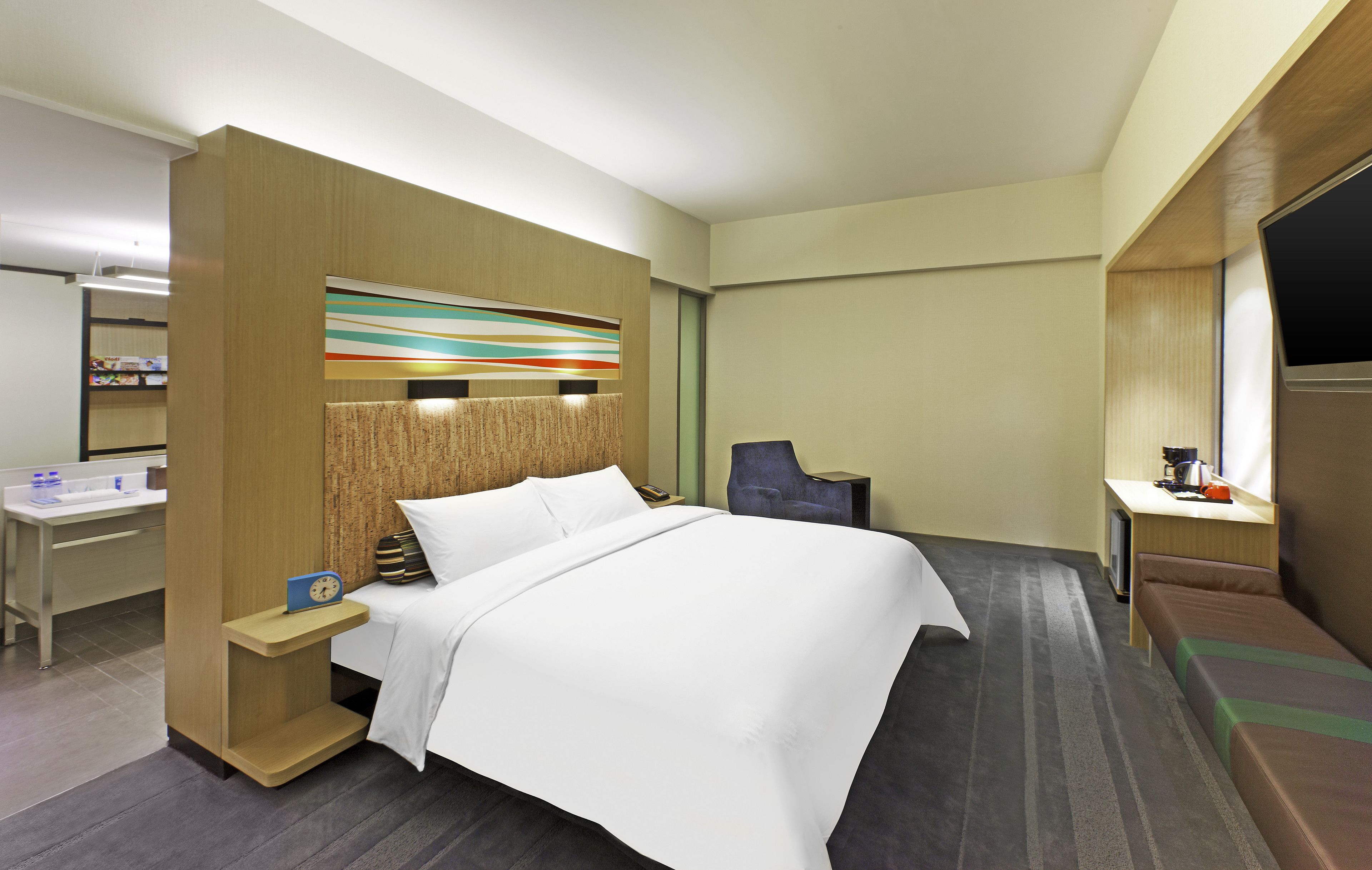 Una habitación de hotel con una cama, un escritorio, una silla, un televisor y una estantería.